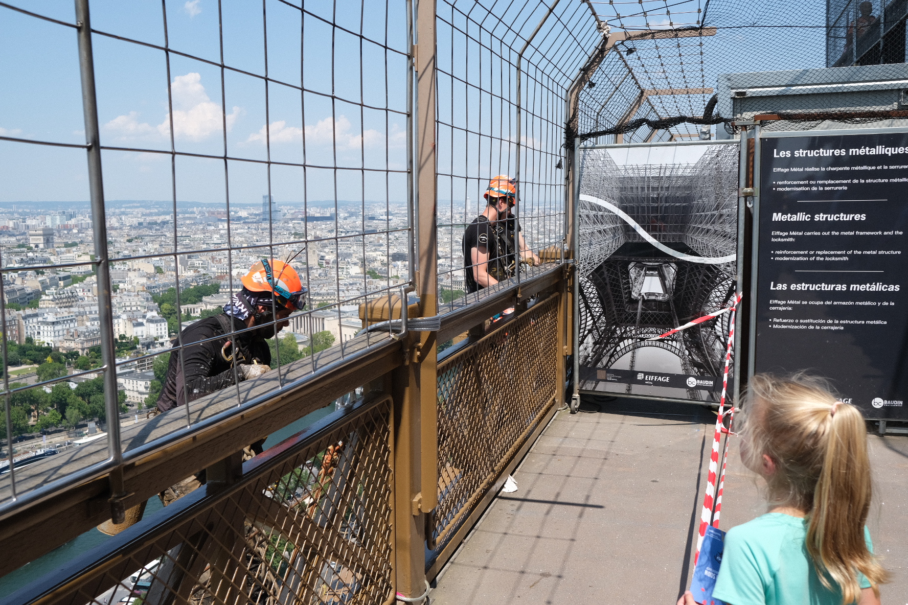 Photo of painters working on the Eiffel Tower, outside the second story deck.